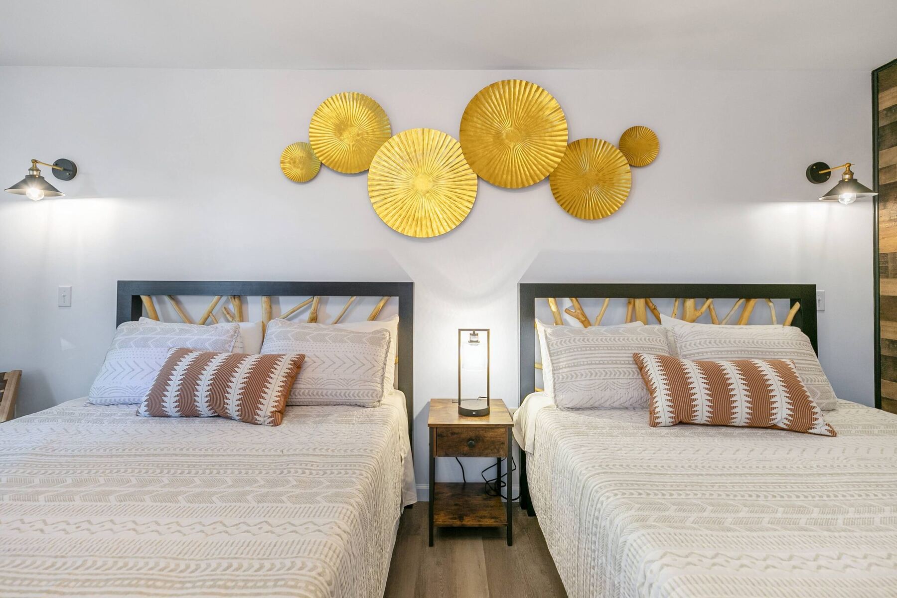 Remodeled room with two queen beds under gold sunburst wall art