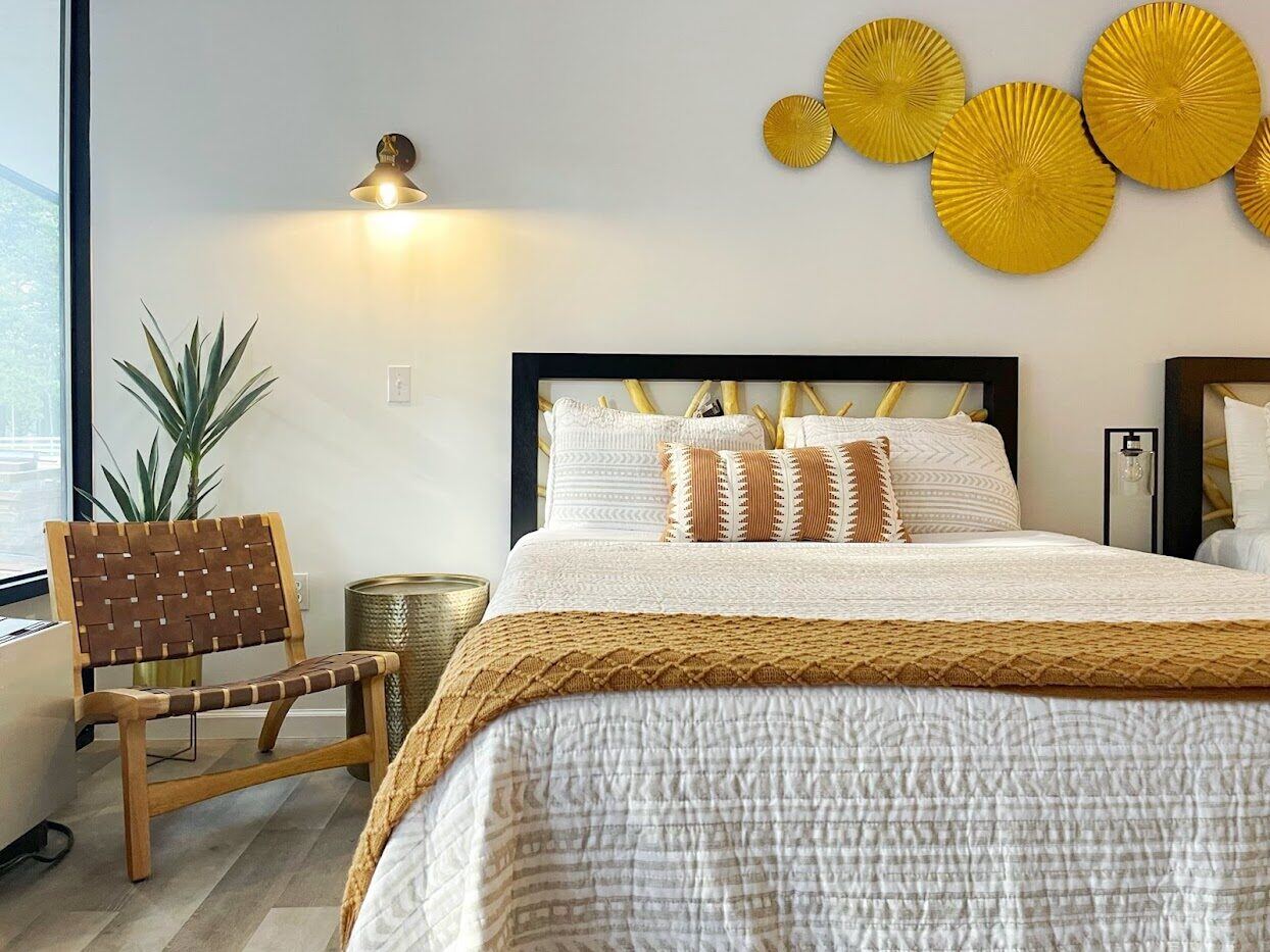 Remodeled king room with gold sunburst wall art and a woven leather chair