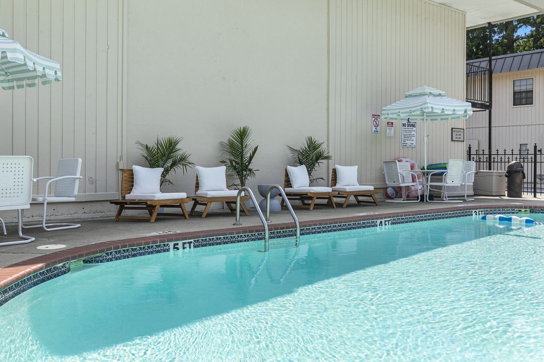 Loungers with white cushions along the pool