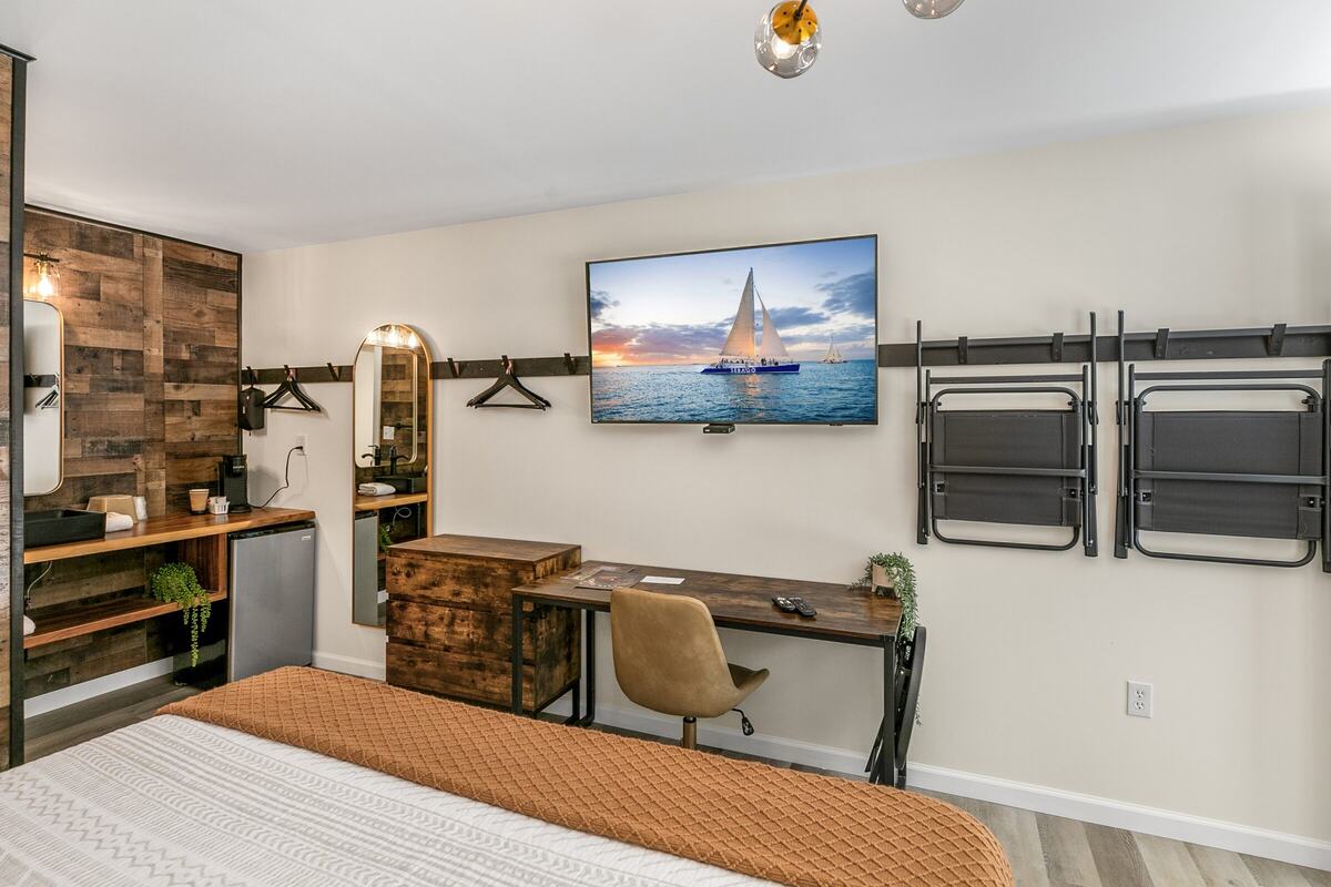 Desk, wall-mounted TV and hanging rail in a remodeled king room