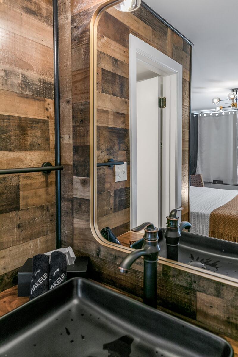 Vanity with a black sink against a reclaimed-wood wall